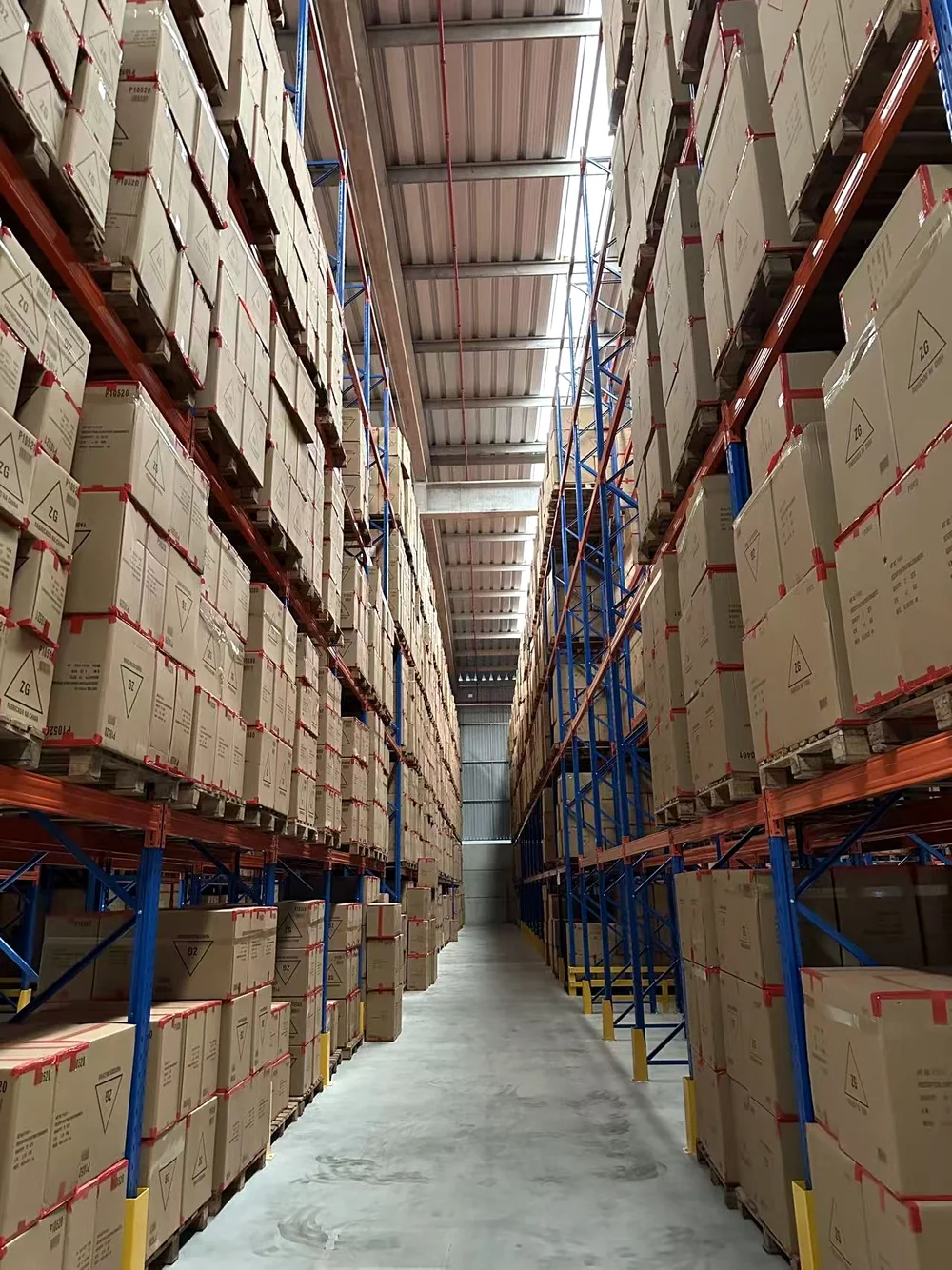 Corredor do galpão da Global Importadora com caixas organizadas em estruturas de armazenagem